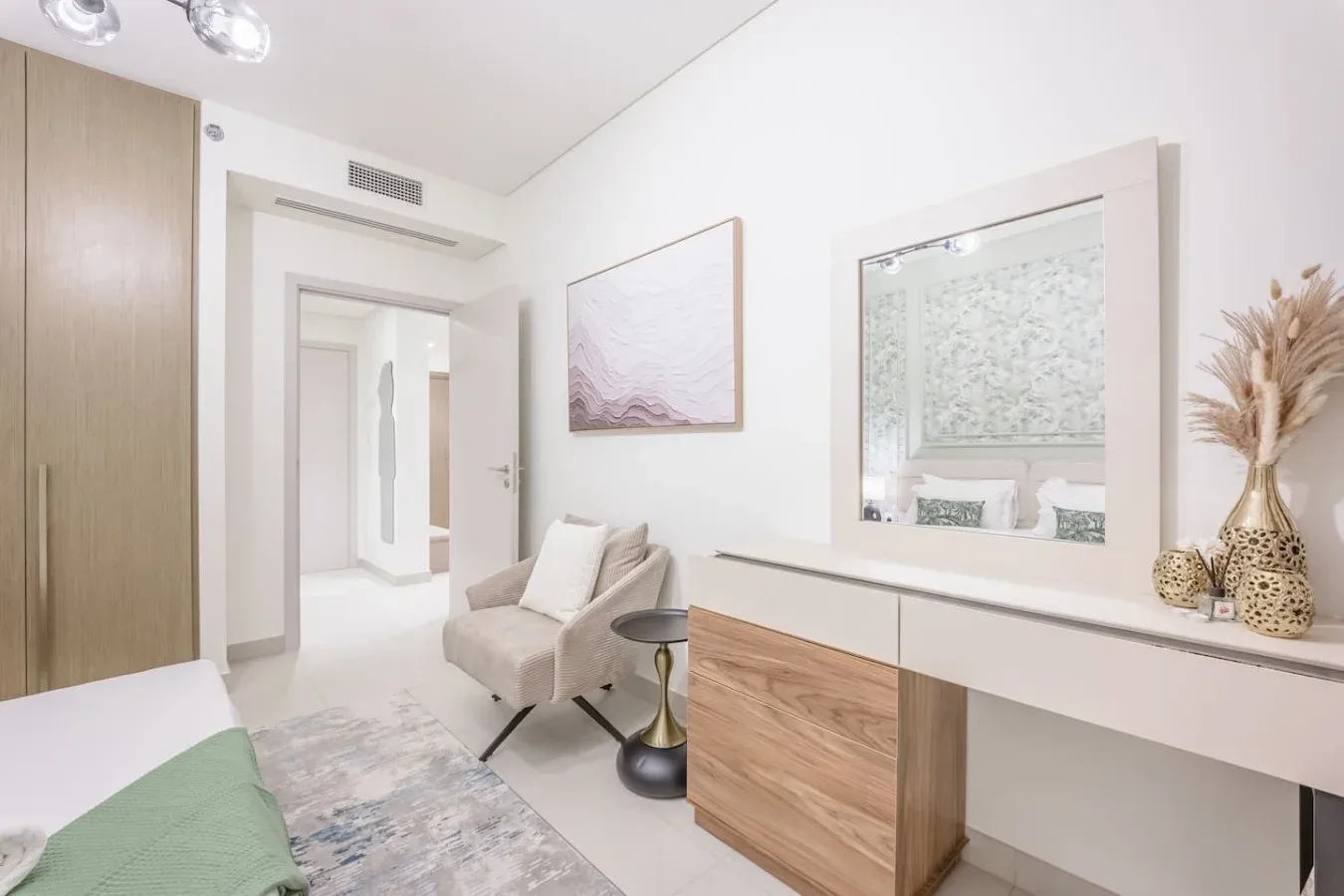 Una luminosa zona de estar con un sillón claro junto a un tocador largo.