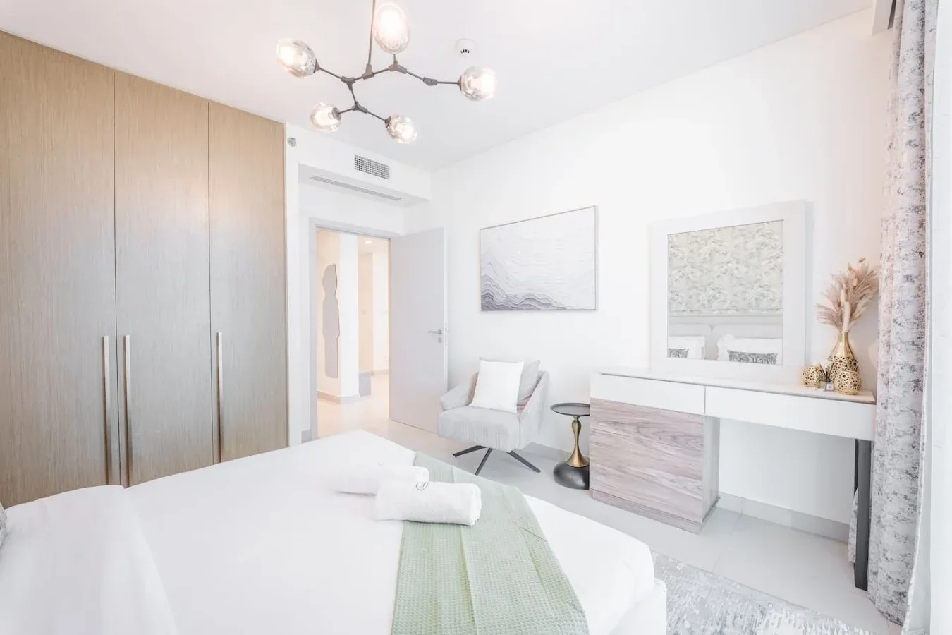 Un dormitorio luminoso con una cama bien hecha, armarios empotrados y un escritorio.