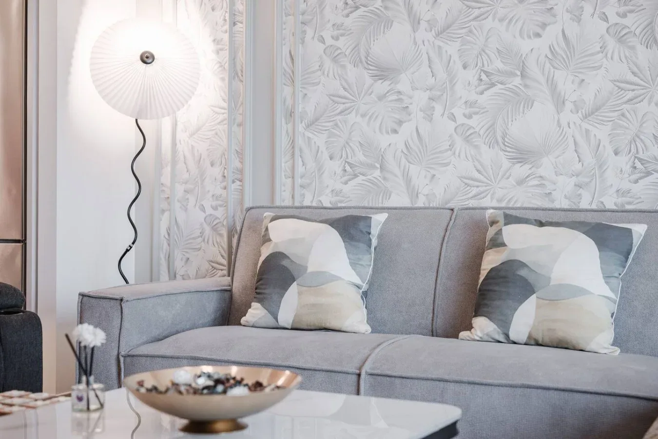 Una sala de estar con un sofá gris y cojines estampados.