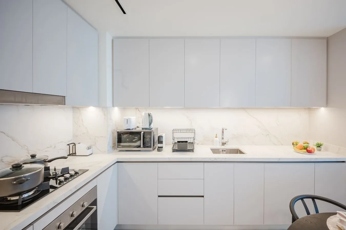 Una cocina moderna y luminosa con gabinetes blancos, encimera y estufa.