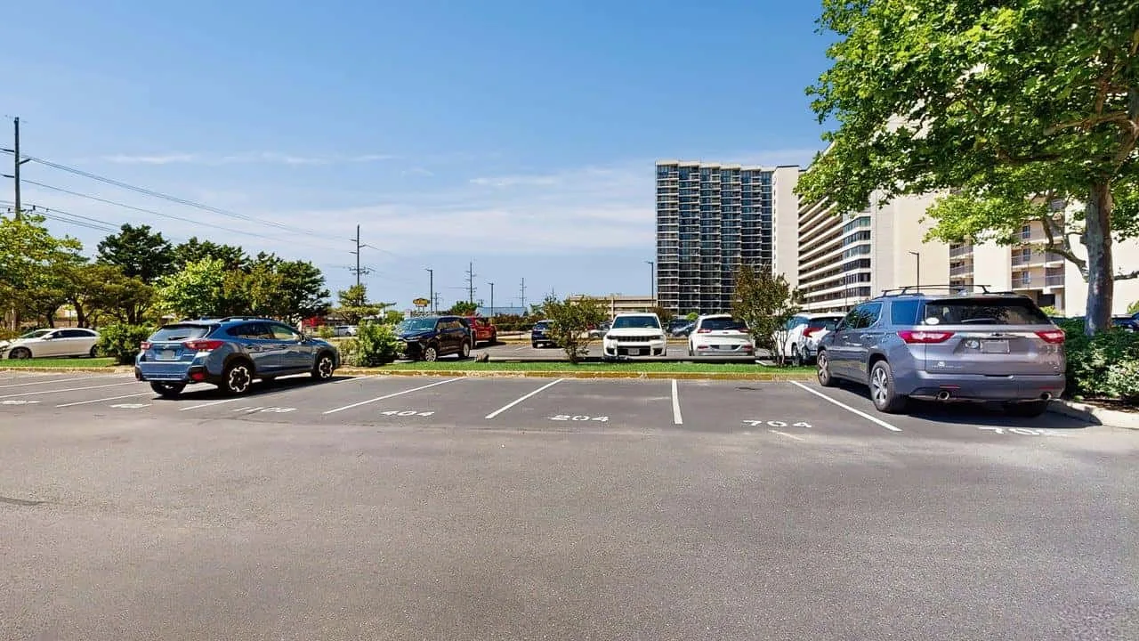 A parking lot with parked cars and apartment buildings in the background.
