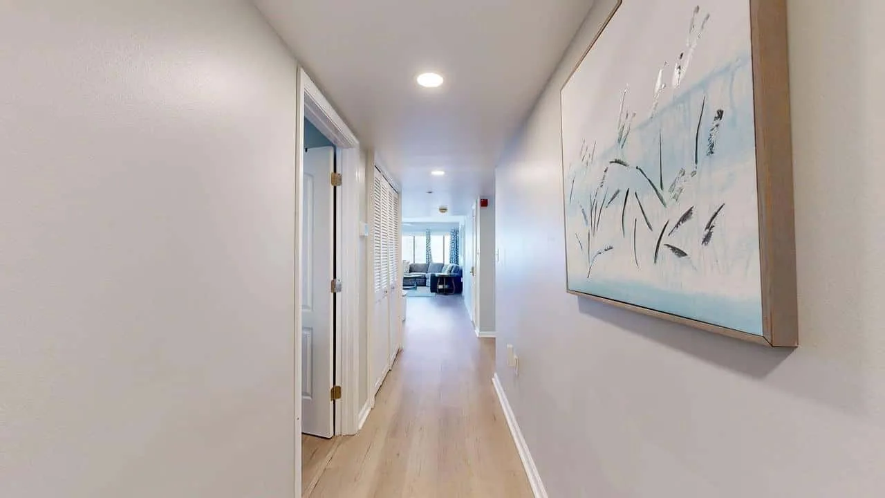 A bright hallway with light wood flooring and framed artwork.