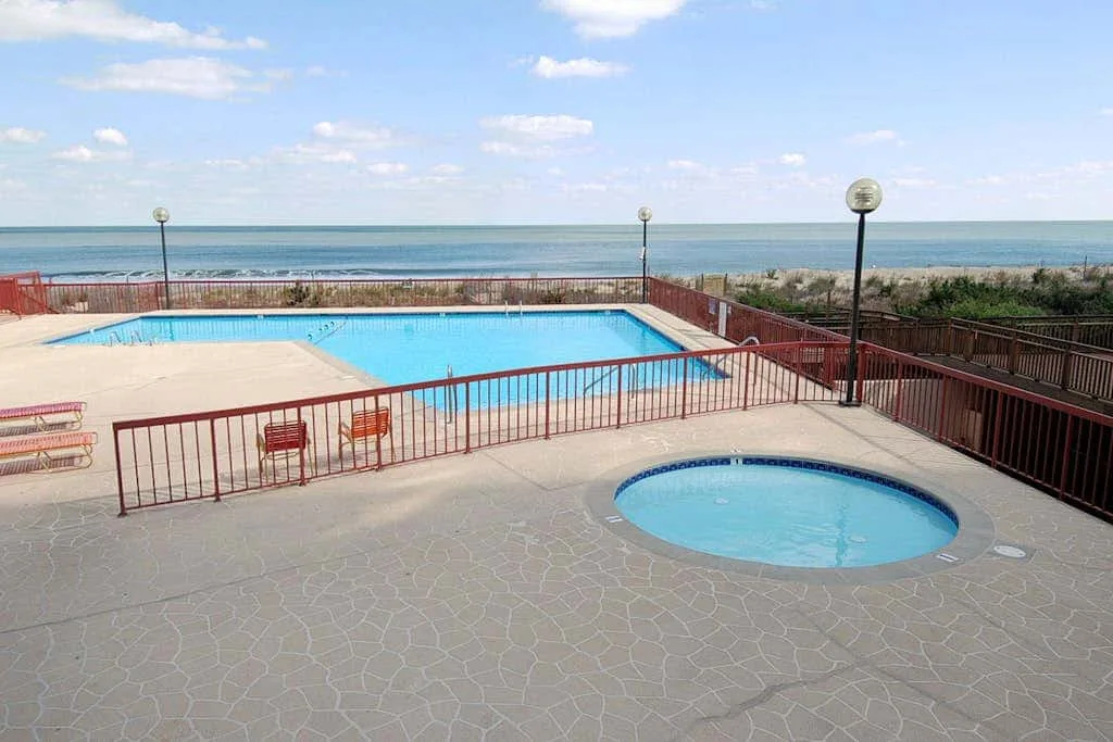An outdoor pool area overlooks the ocean, with a smaller round pool in front.