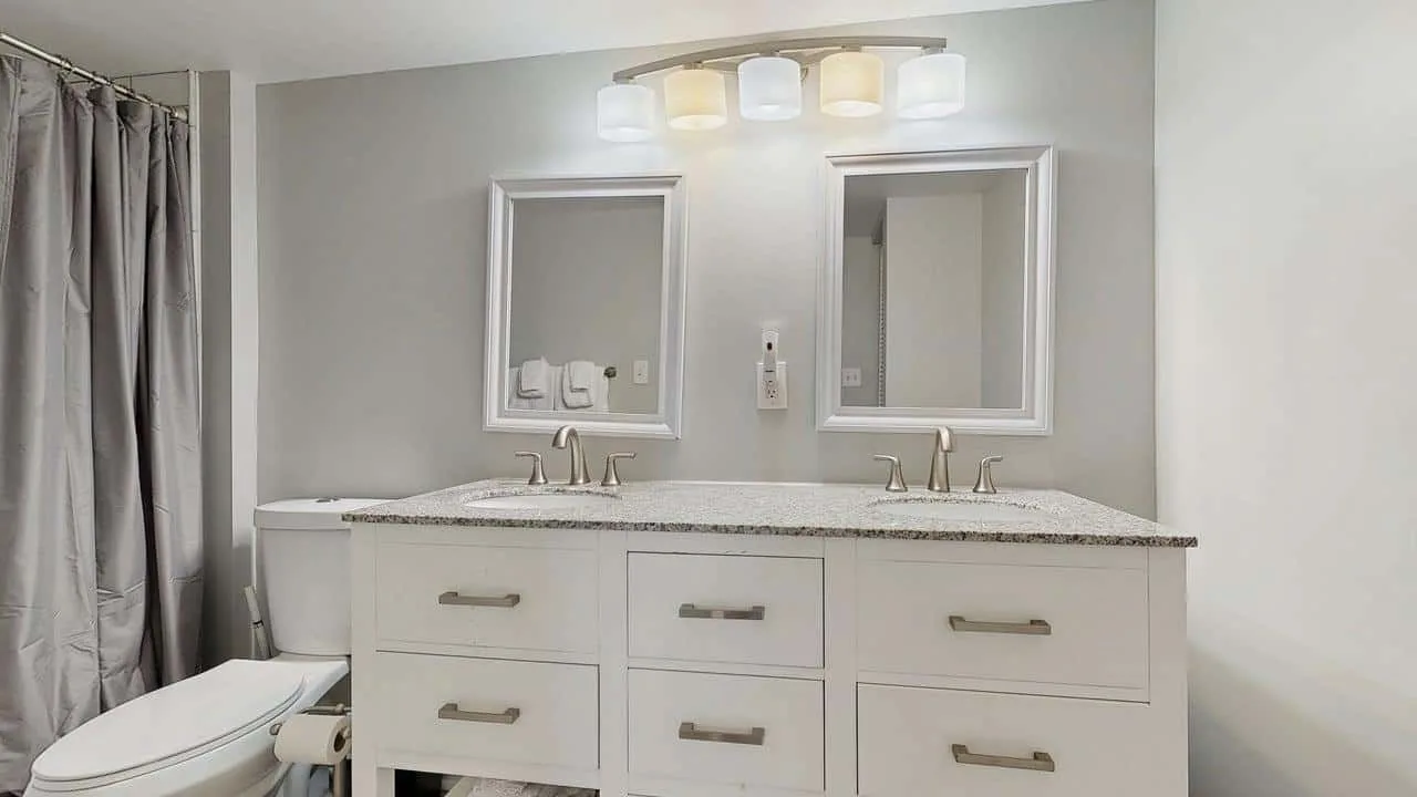 A bathroom vanity with two mirrors and a shower curtain.