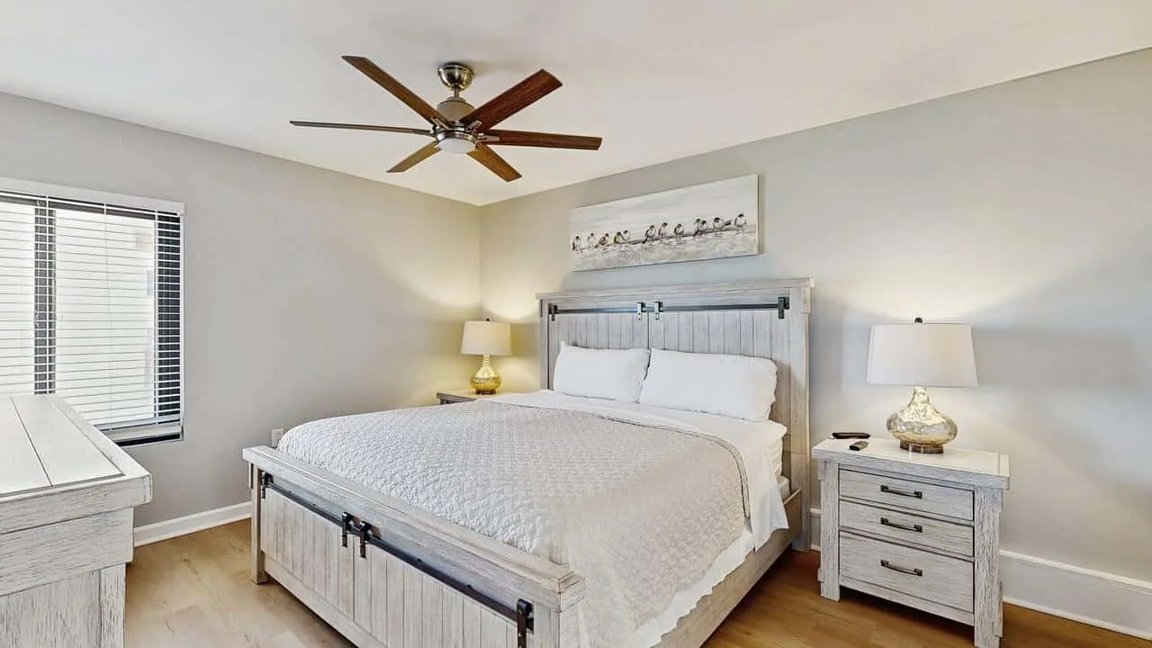 A bedroom with a bed, matching bedside tables, and a ceiling fan.