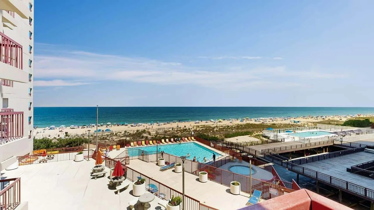 A swimming pool and lounge area overlook the beach and sea.