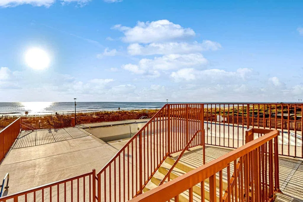 A seaside deck with red railings overlooks the ocean.