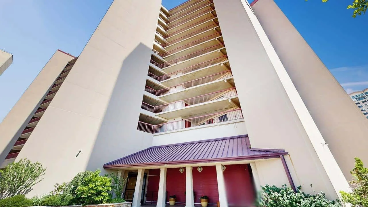 A tall apartment building with stacked balconies and a covered entrance.