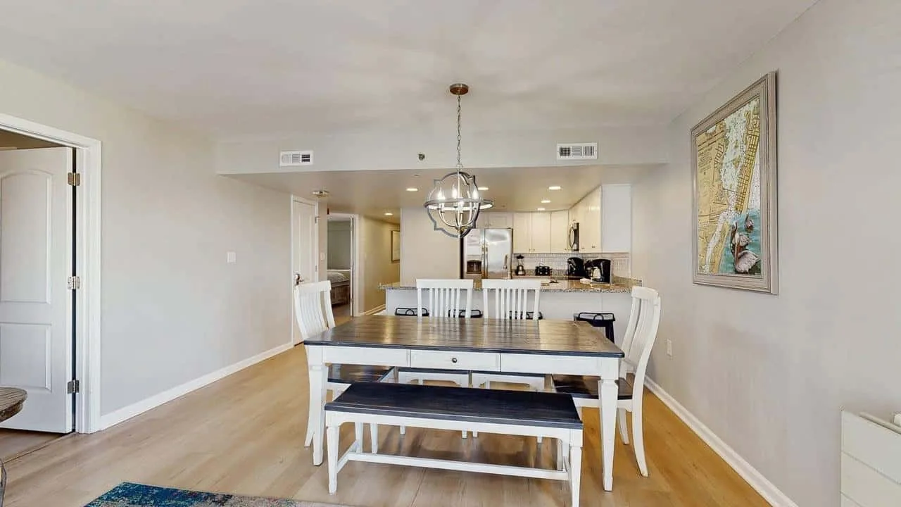 An open-plan dining area with a table and kitchen in the background.