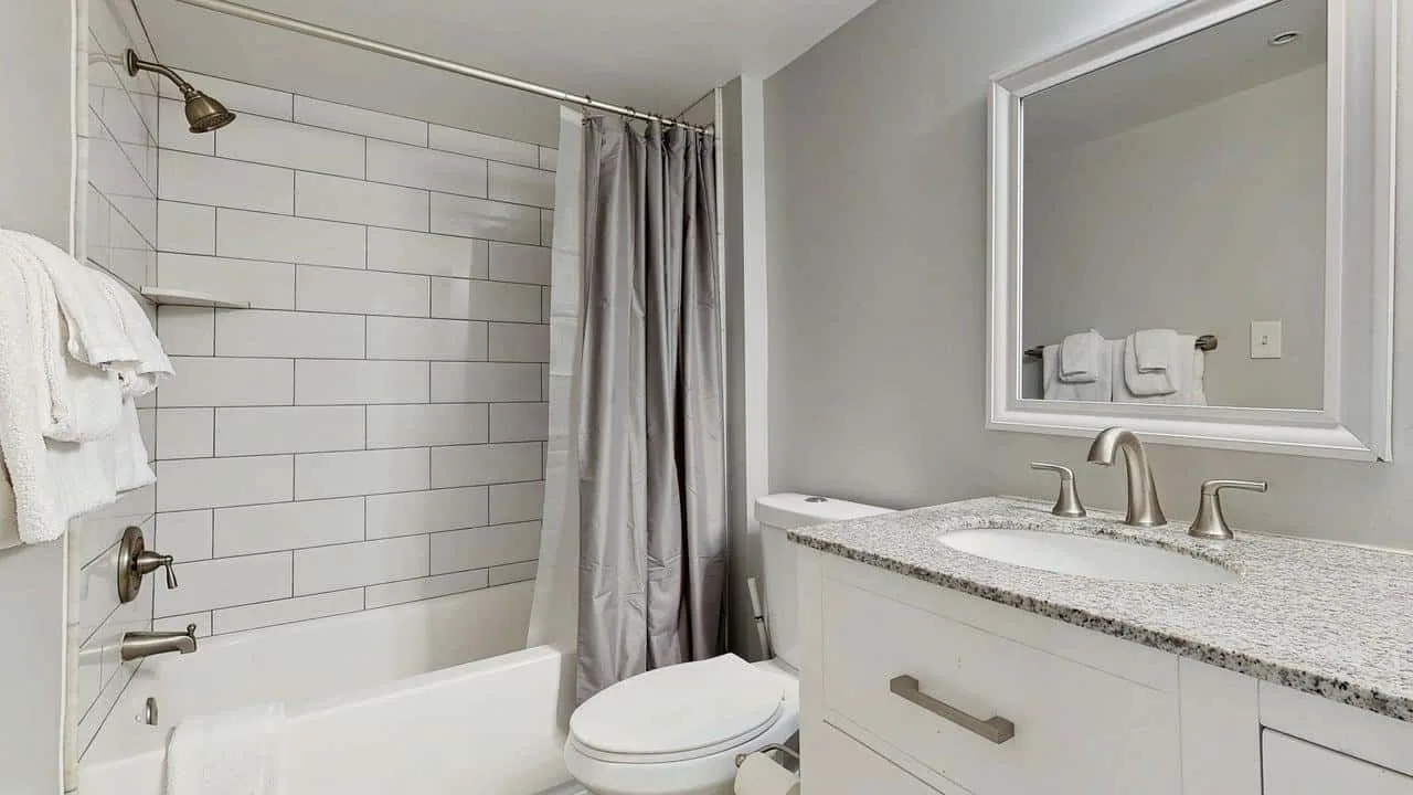 A bathroom with a bathtub, shower curtain, and vanity.