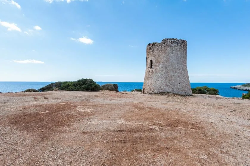 Una torre de piedra se alza en un promontorio rocoso junto al mar.