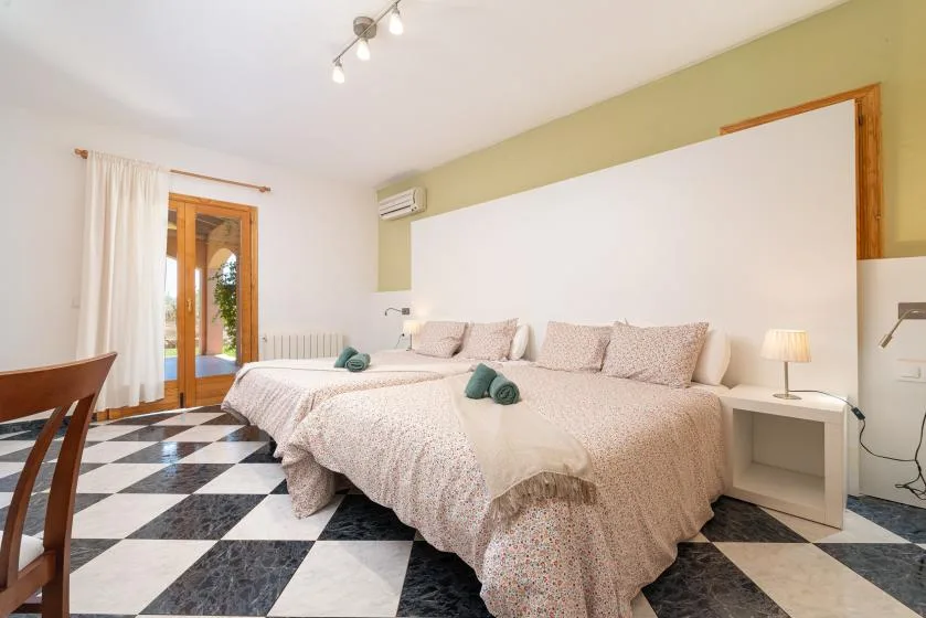 Un dormitorio con una cama grande, ropa de cama estampada y suelo de baldosas blancas y negras.