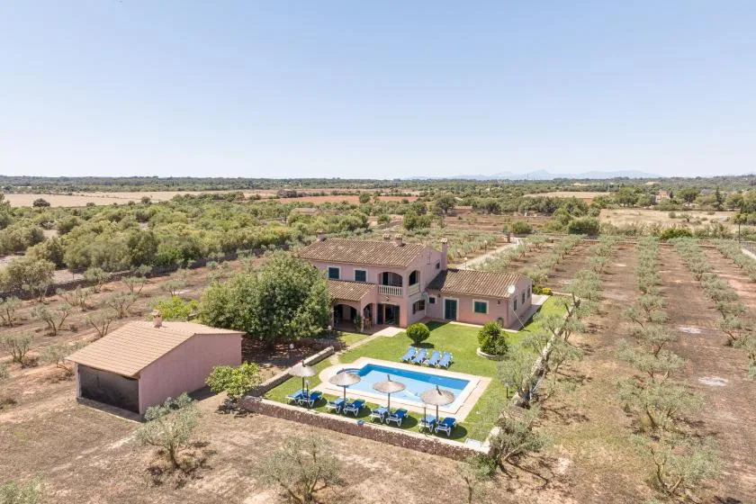 Una propiedad rural con una casa, una piscina y campos secos alrededor.
