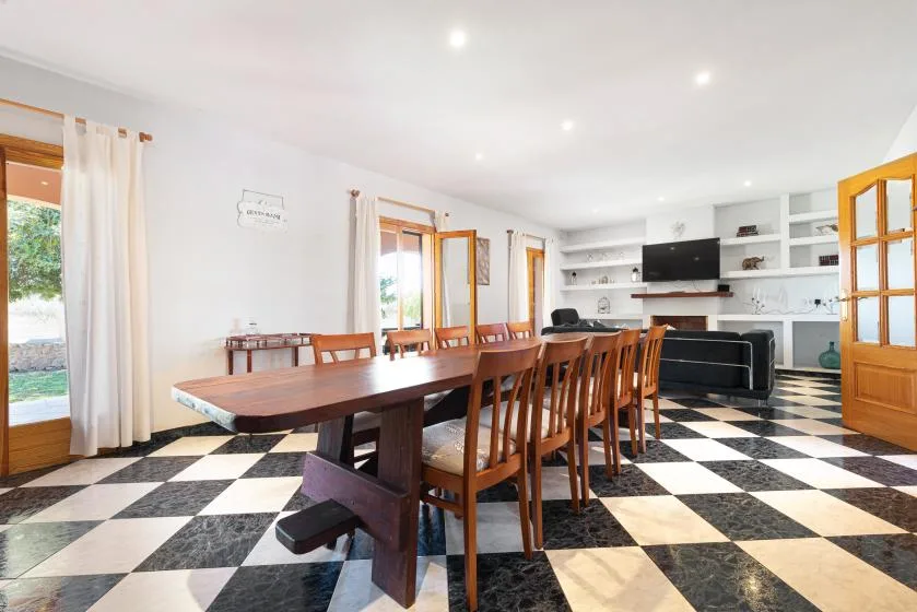 Un comedor con una mesa larga de madera, sillas y un suelo de baldosas blancas y negras.