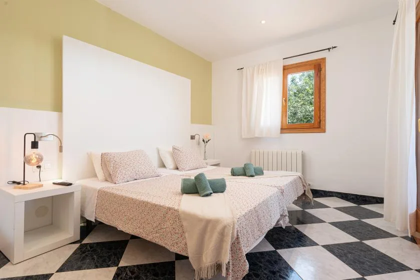 Un dormitorio con una cama doble, mesillas de noche y suelo a cuadros.