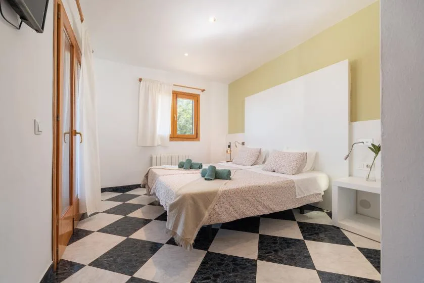 Un dormitorio con dos camas, una ventana y un suelo de baldosas blancas y negras.