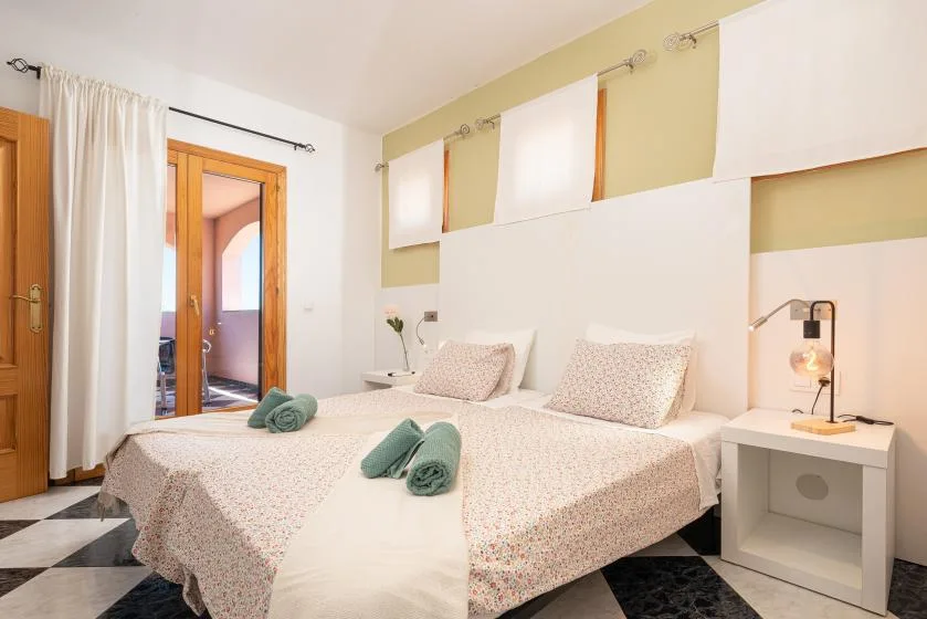 Un dormitorio con dos camas, ropa de cama estampada y una mesita de noche.