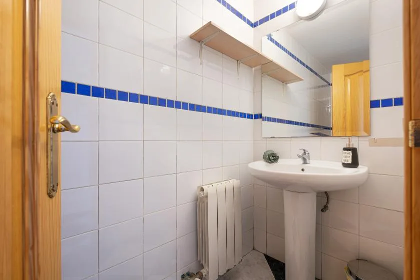 Un baño alicatado con un lavabo con pedestal y un radiador de pared.