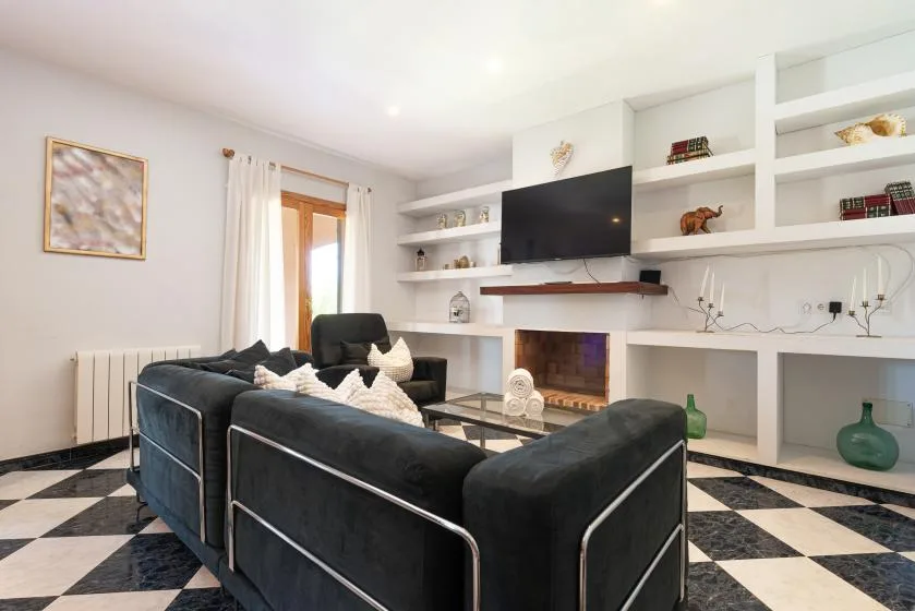 Una sala luminosa con asientos oscuros, un televisor y una chimenea.