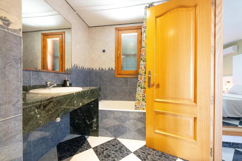Un baño con lavabo, bañera y una puerta de madera abierta.