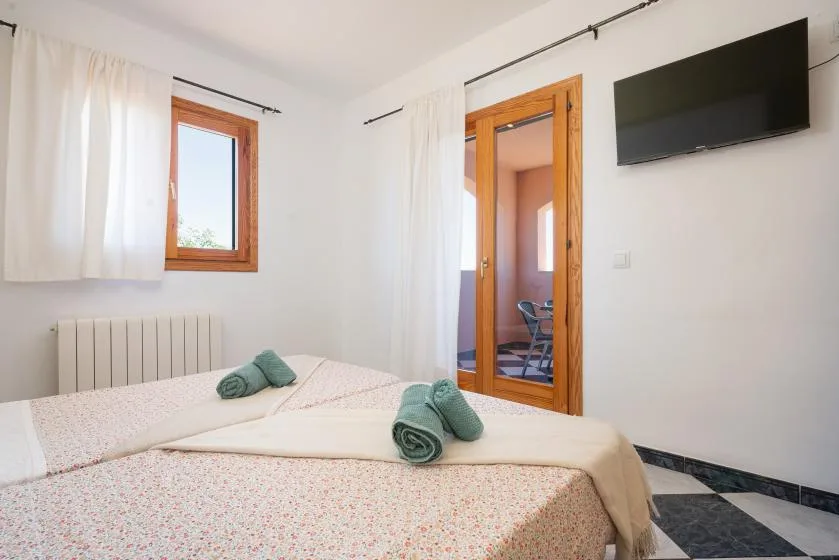 Un dormitorio con una cama, una ventana y un televisor en la pared.