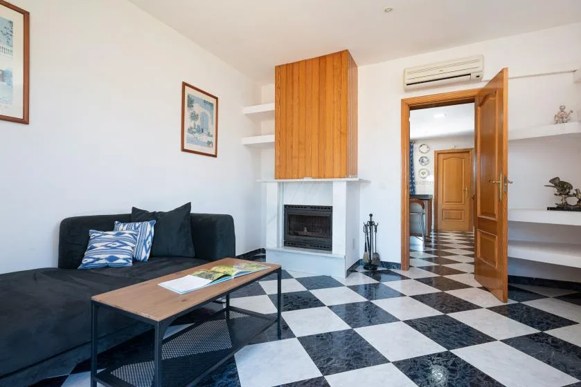 Sala de estar con zona de asientos oscura, mesa de centro y chimenea.