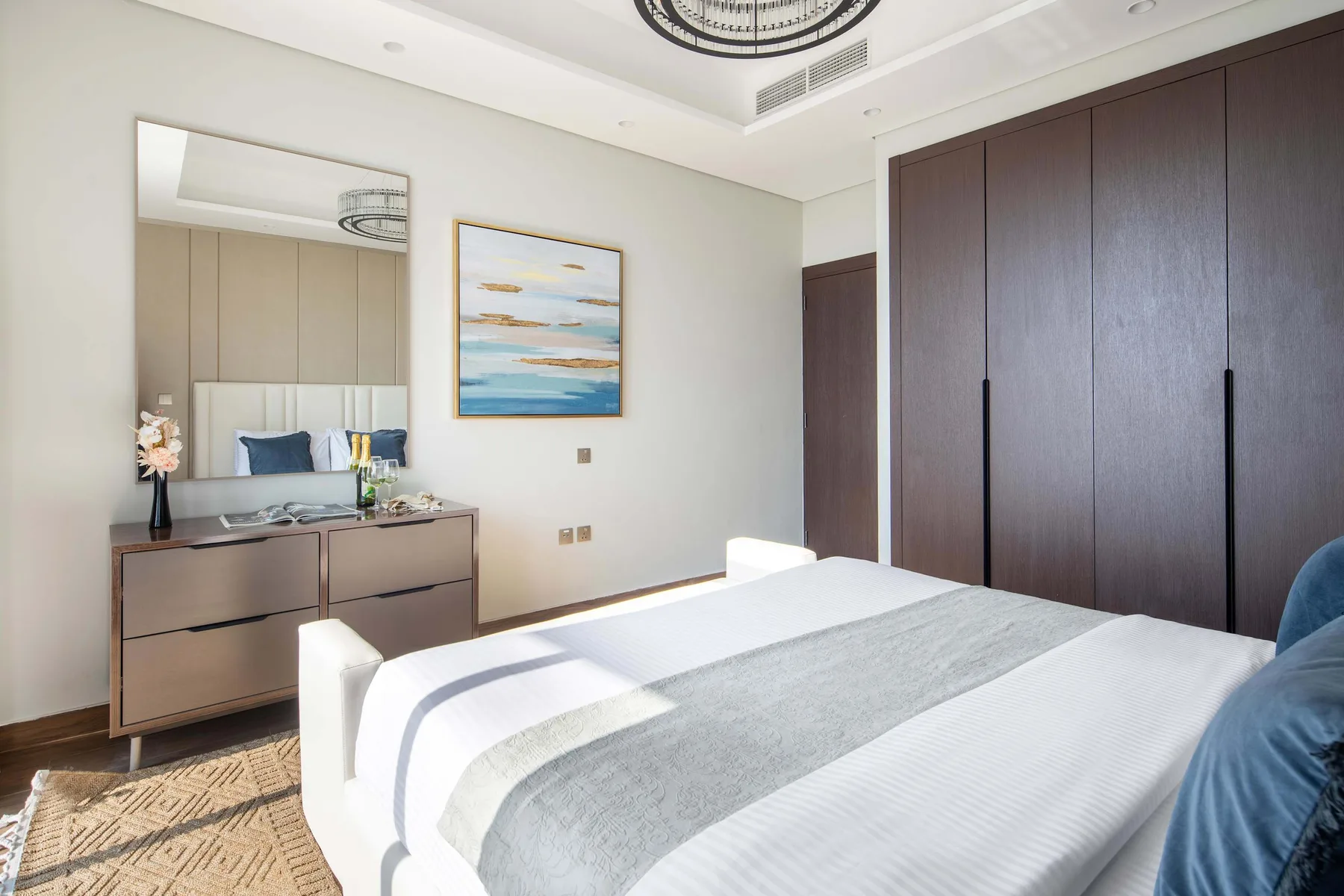 A bedroom with a neatly made bed and a large dark wardrobe.