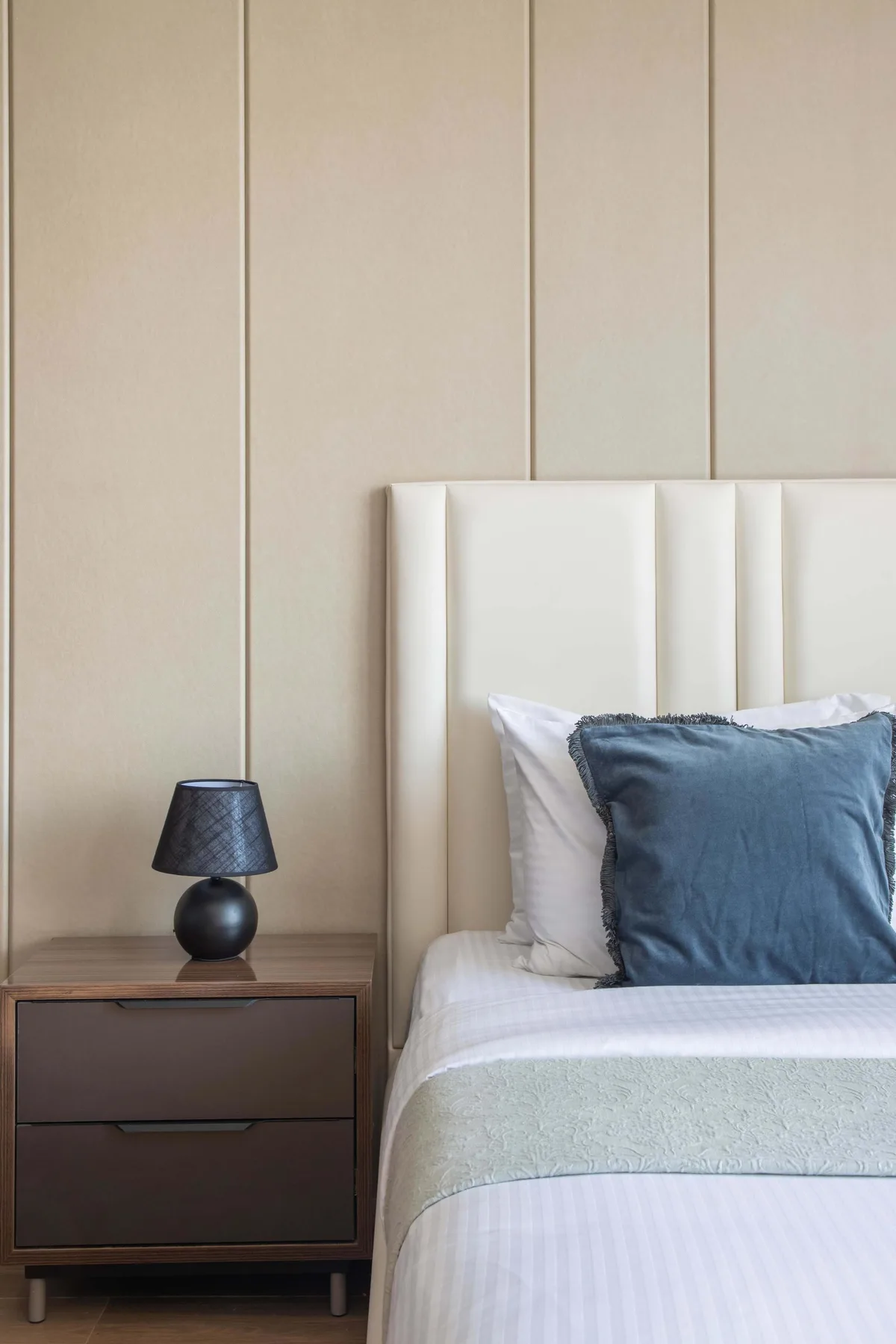 A bedroom with a neatly made bed and a bedside table.