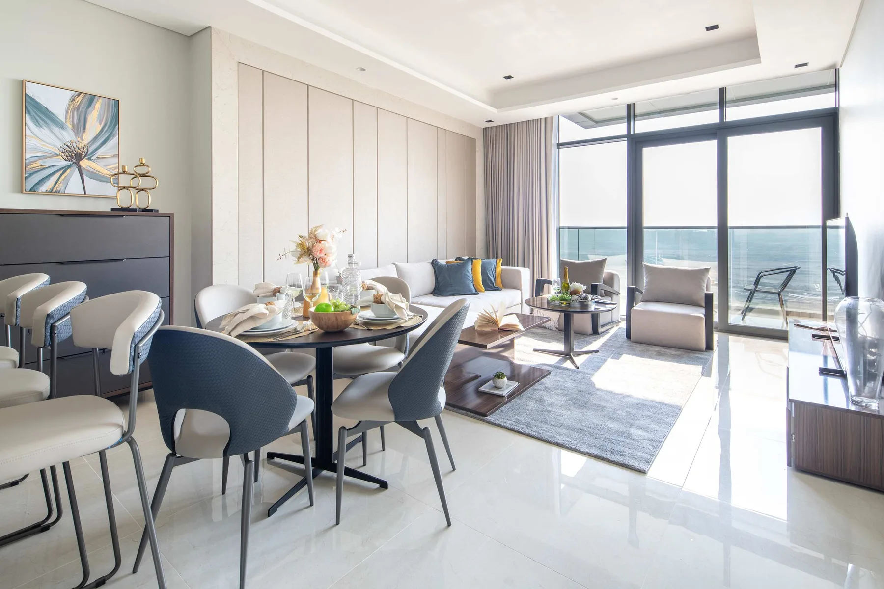 Sala de estar con comedor y grandes ventanales frente al agua.
