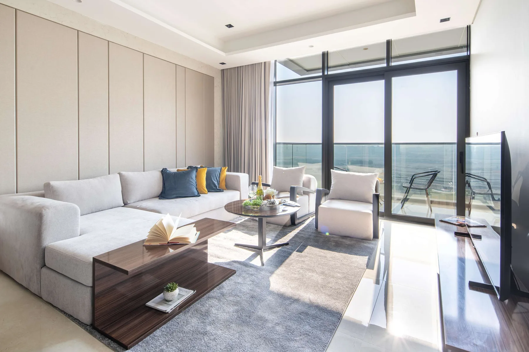 Sala de estar luminosa con ventanales y vistas al mar.