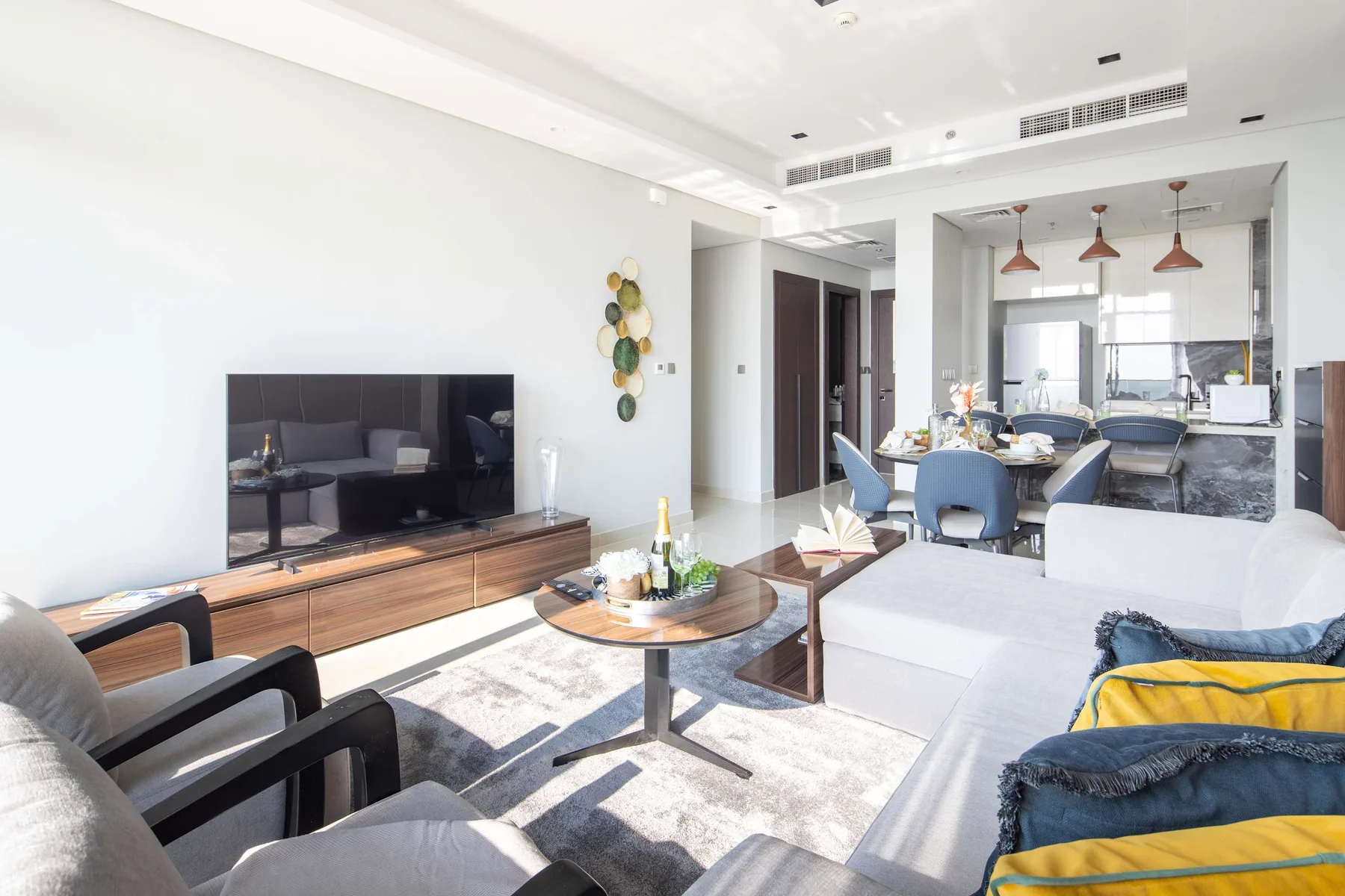 Bright living room with seating, a television, and a dining area beyond.