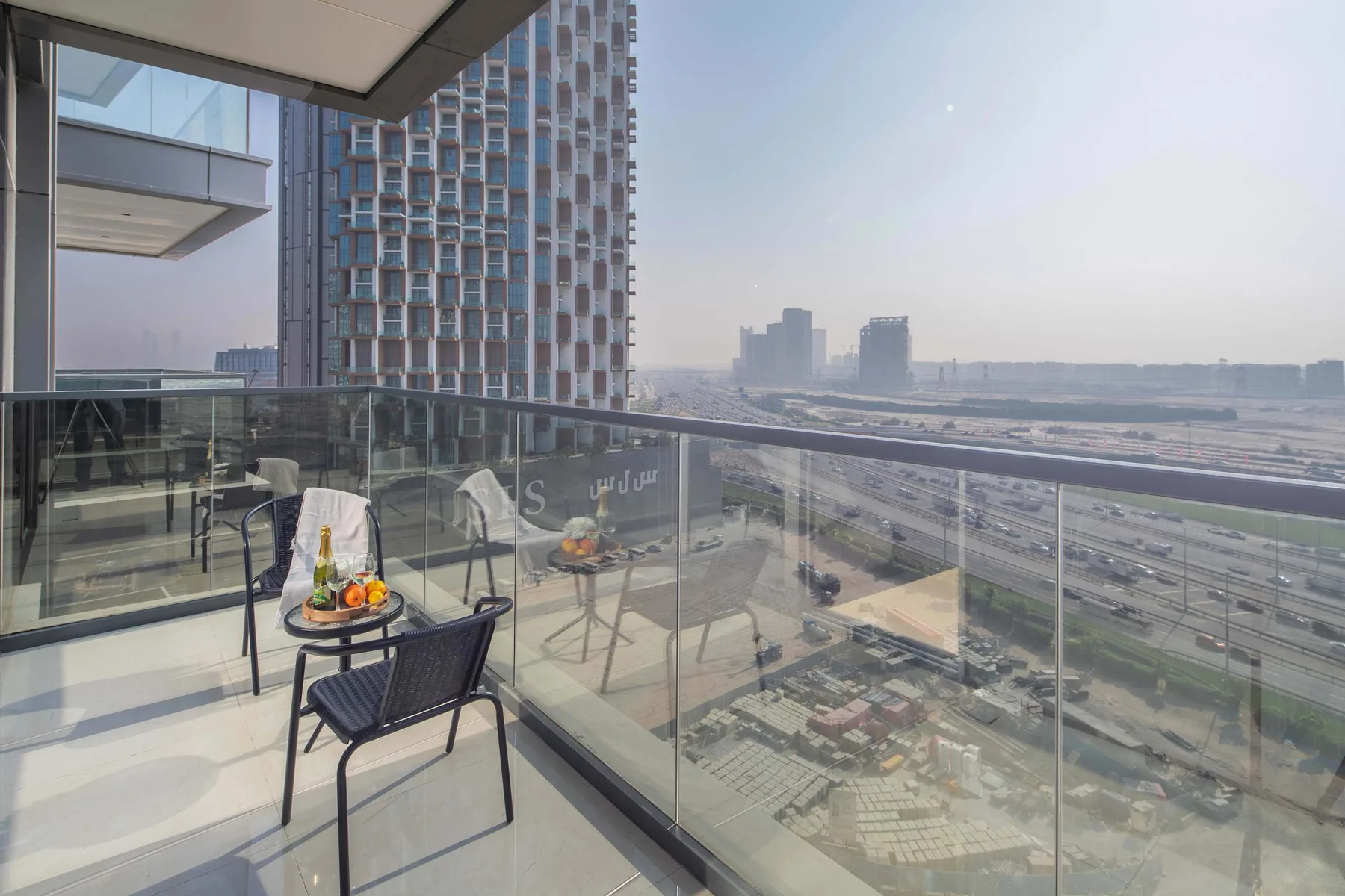 A balcony seating area overlooks a city skyline and roads.