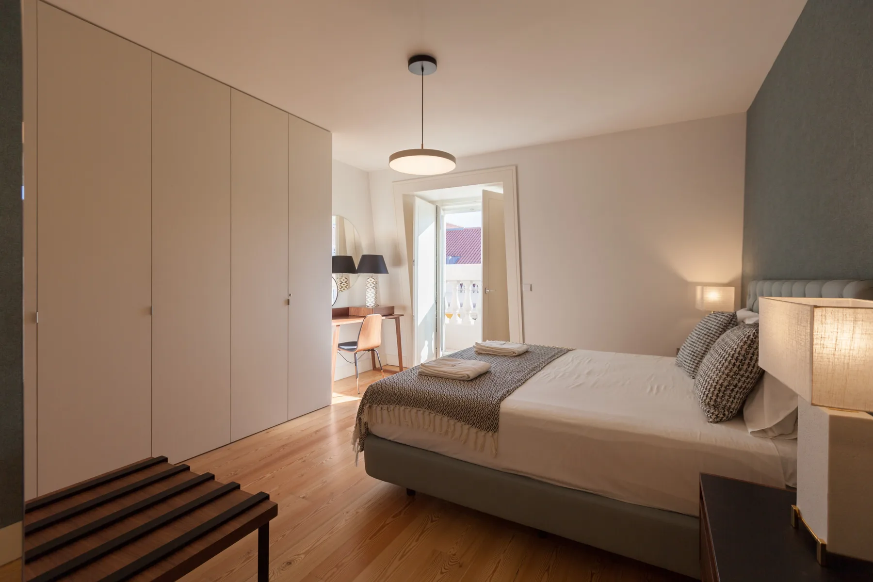 A bedroom with a bed, built-in wardrobes, and a doorway opening onto a balcony.