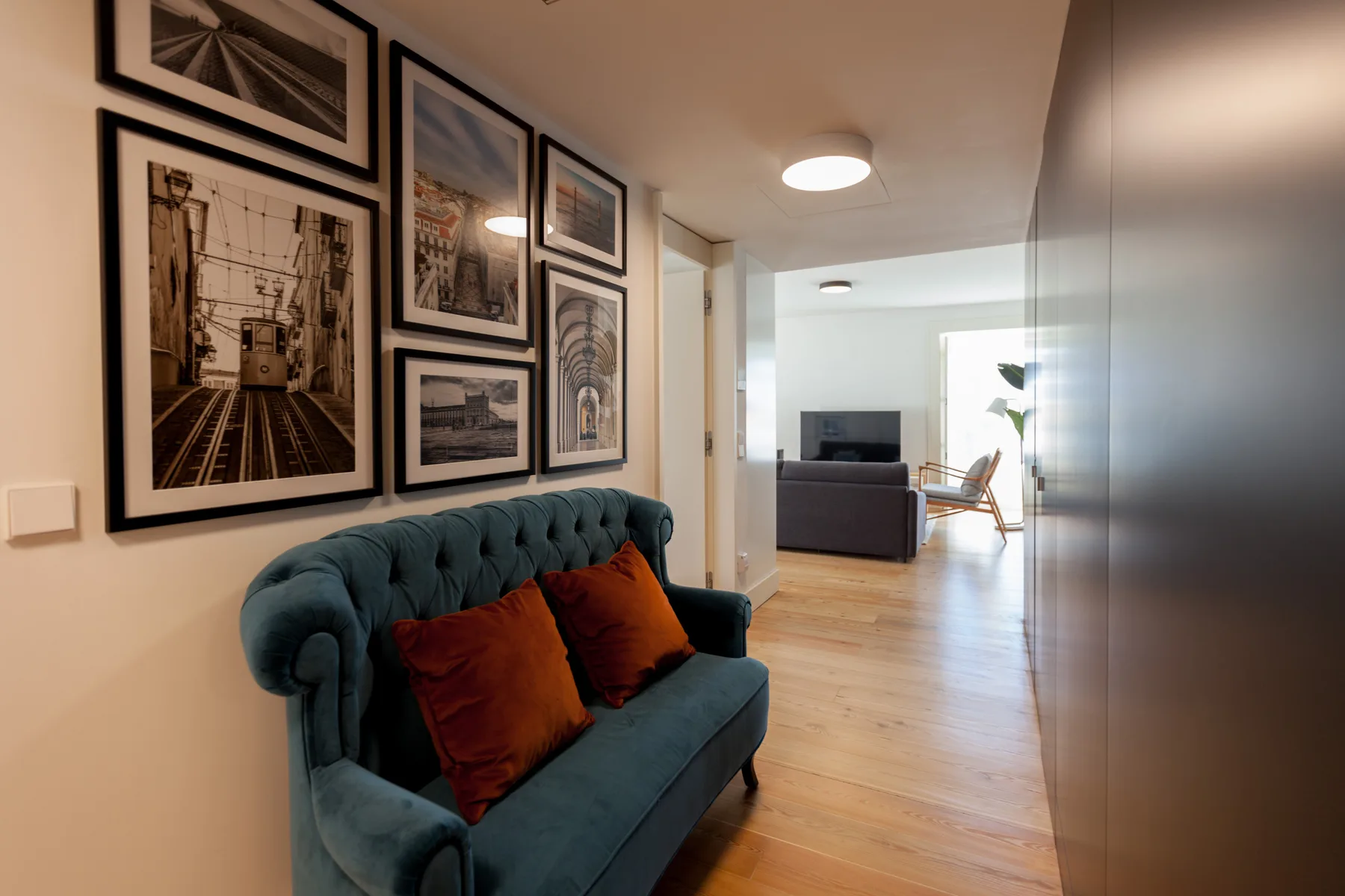 A living room with a teal sofa and framed artwork along the wall.