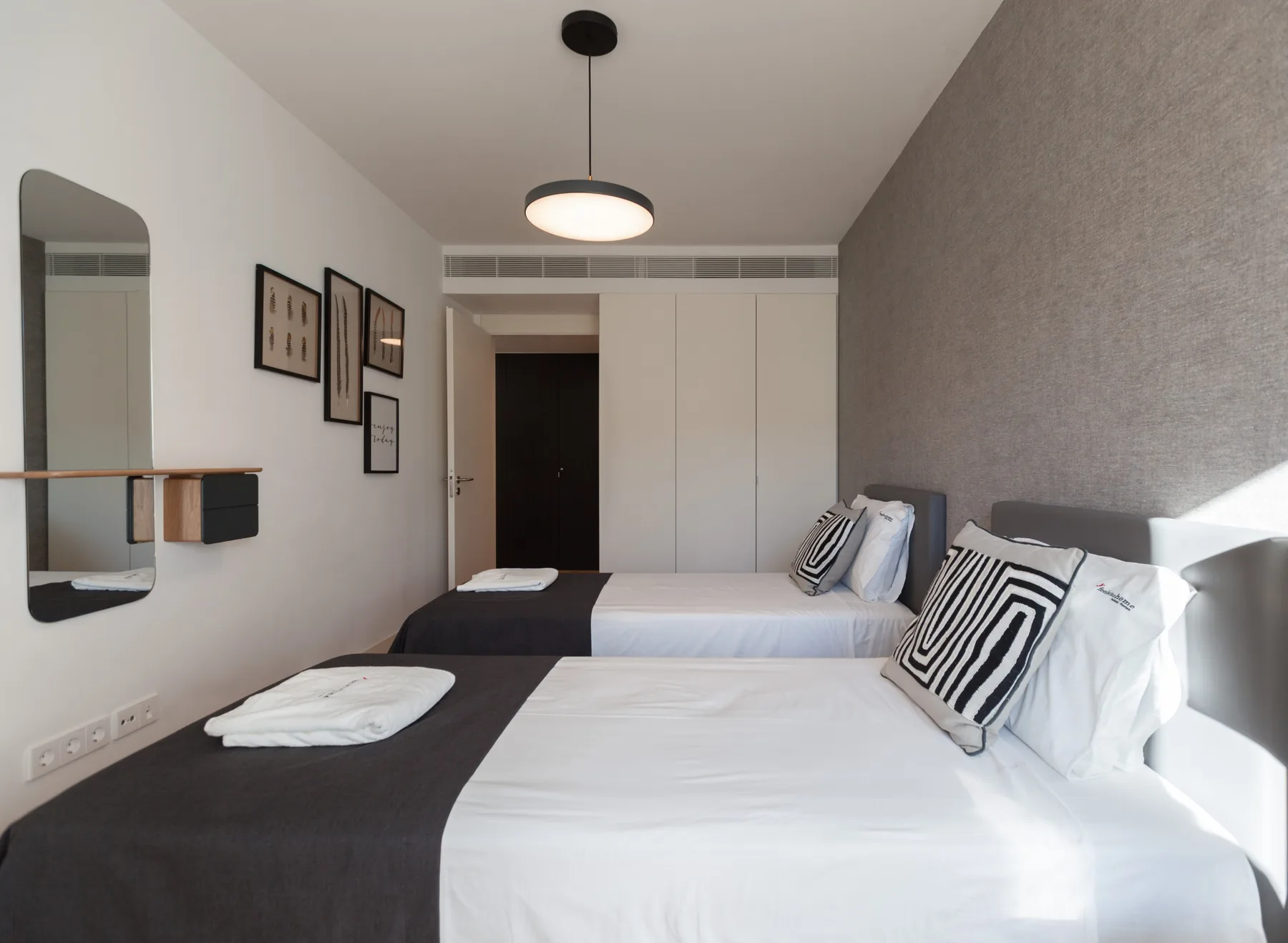 A bedroom with two beds and a gray accent wall.