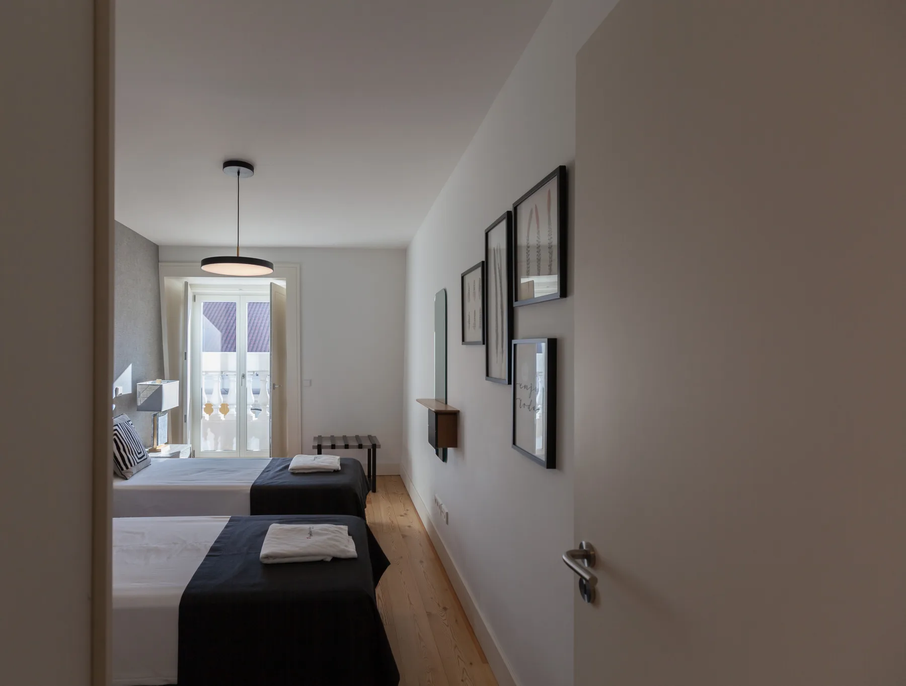 A bedroom with two beds and framed artwork along the wall.