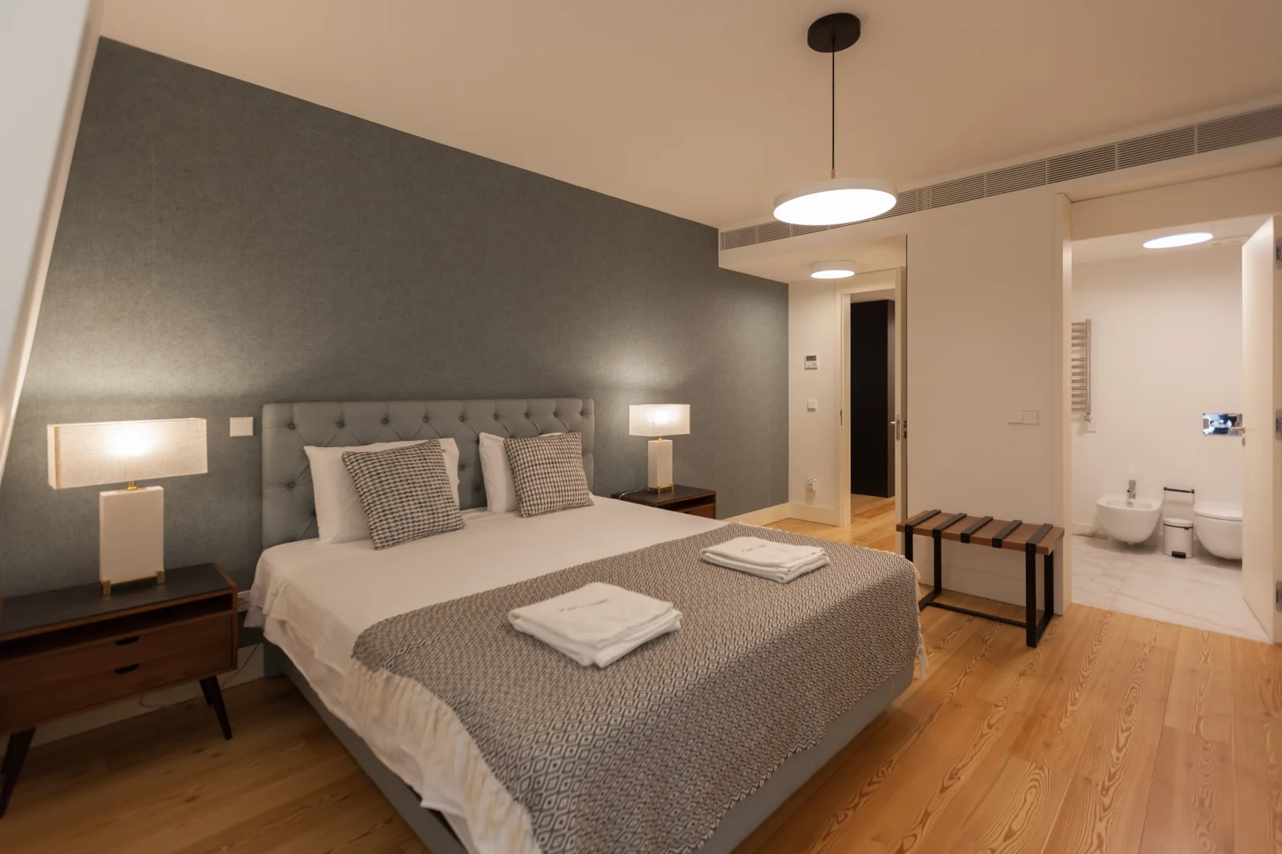 A bedroom with a double bed, bedside tables, and an adjoining bathroom.