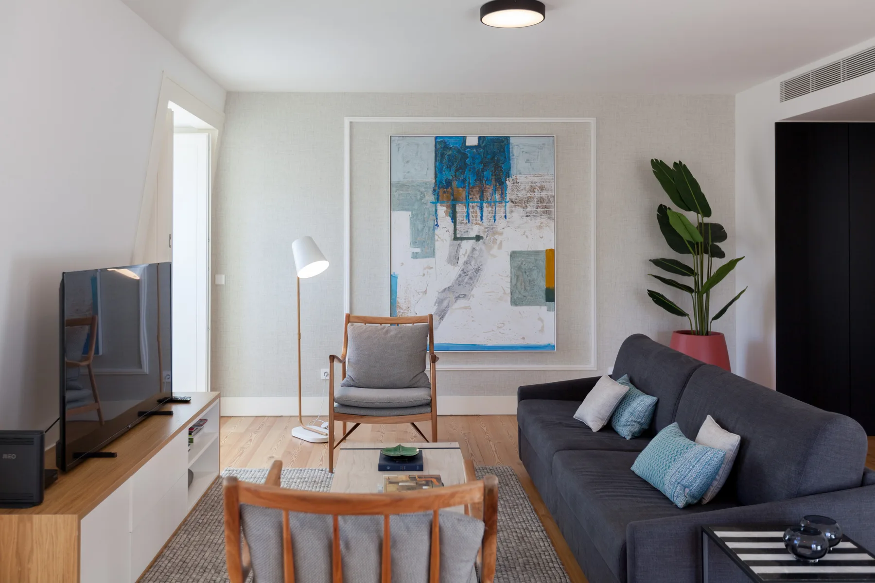 A living room with a dark sofa, a television, and framed artwork.