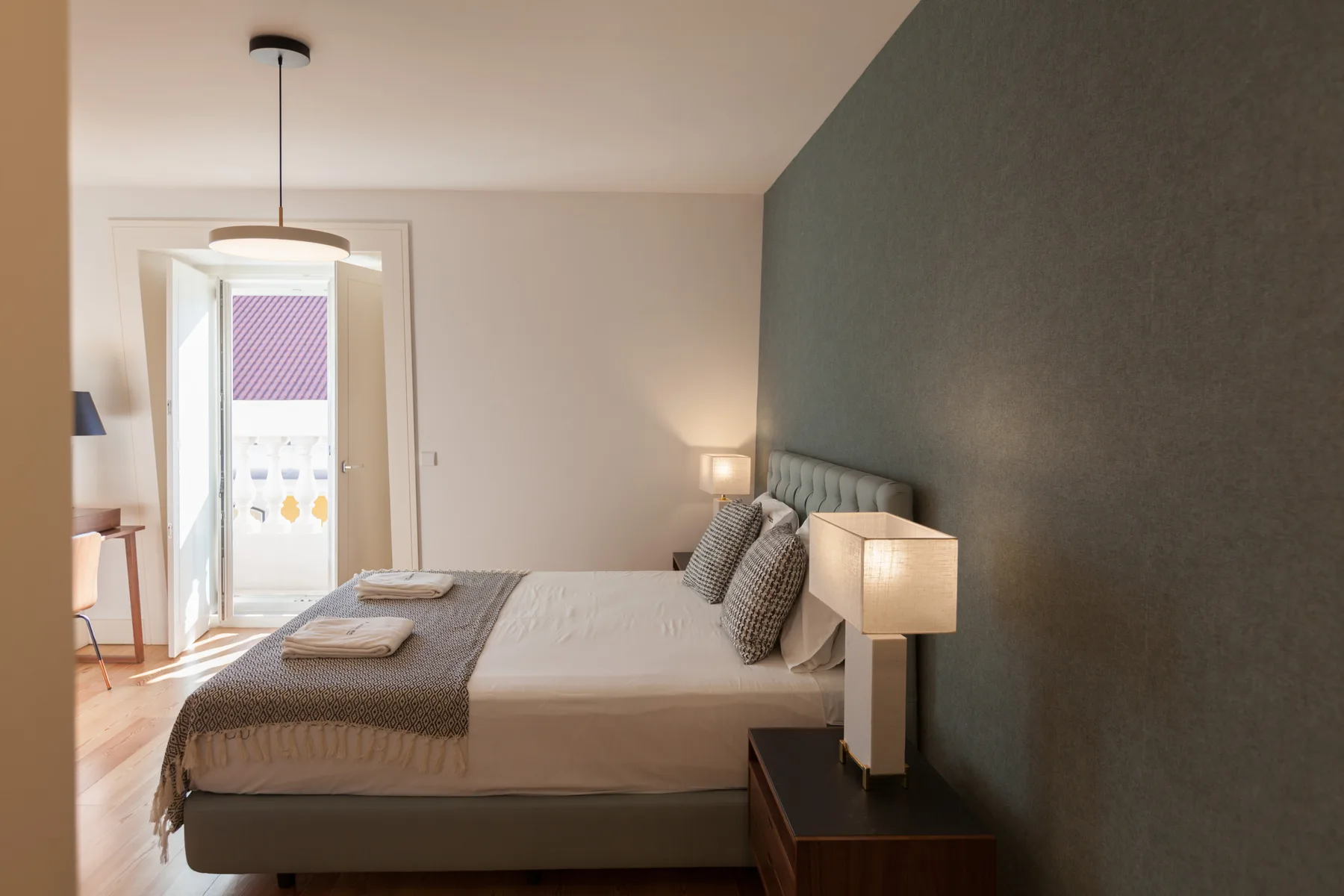 A bedroom with a double bed and a doorway opening onto a balcony.