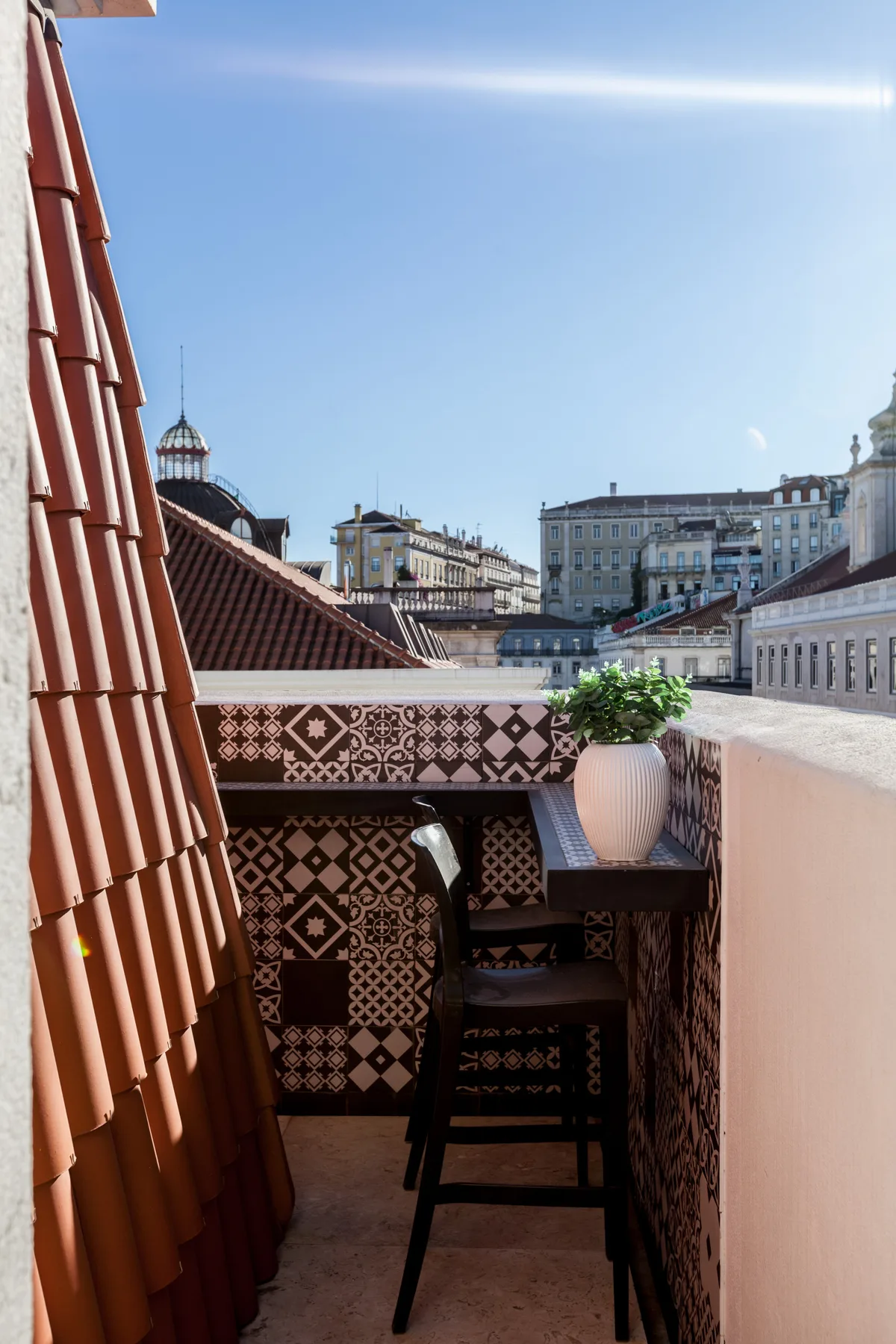 Un balcón con azulejos tiene vistas a los tejados y edificios de la ciudad.