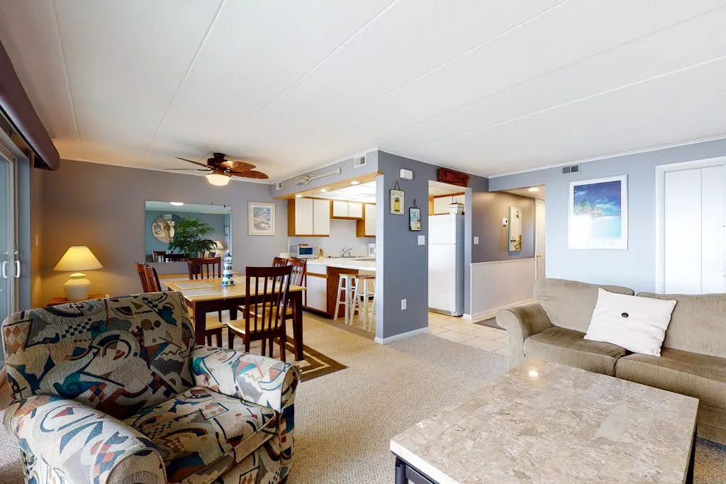 An open-plan living and dining area with patterned seating and a kitchen beyond.