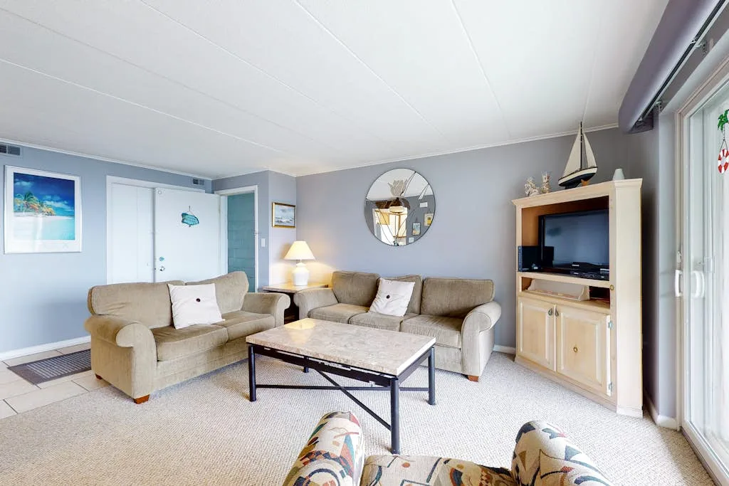 A living room with seating arranged around a coffee table and television.