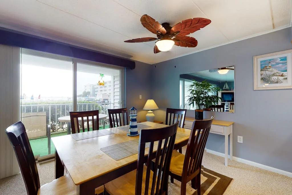 A dining area with a wooden table and chairs beside sliding glass doors.