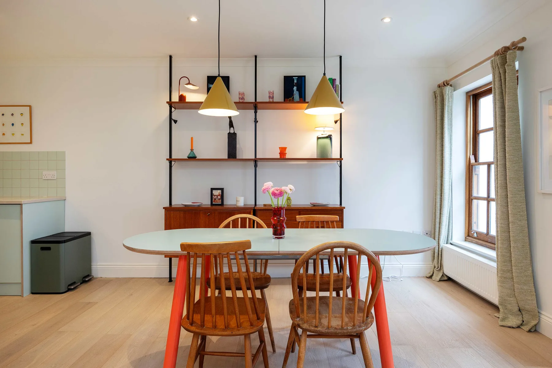 A dining area with a table and chairs beneath two pendant lights.
