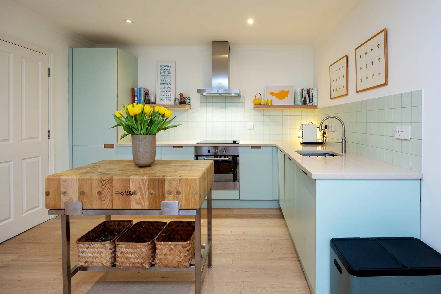A pale blue kitchen with a central wooden island and countertop along the wall.