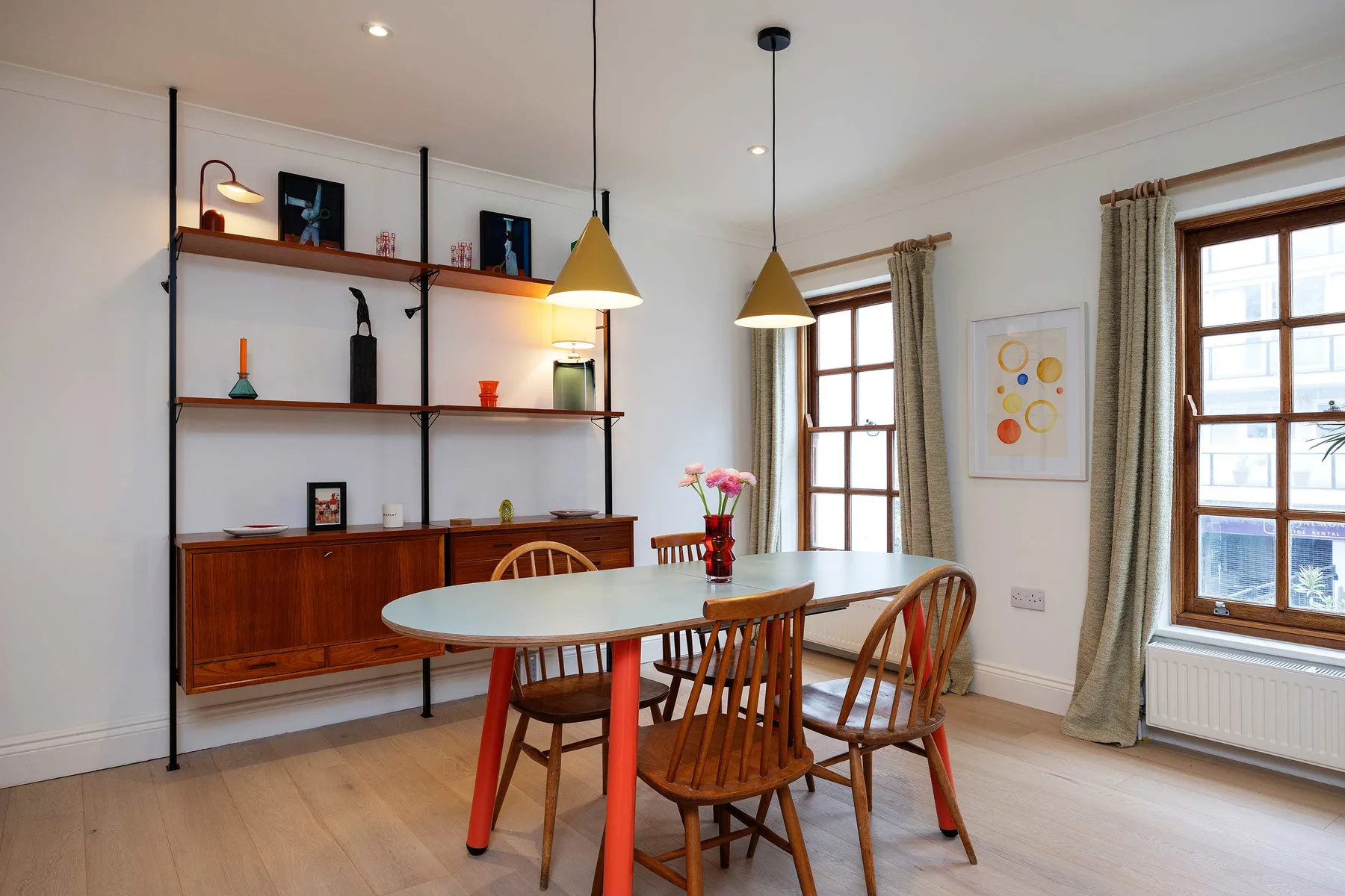 Comedor con una mesa, sillas de madera y estanterías empotradas.