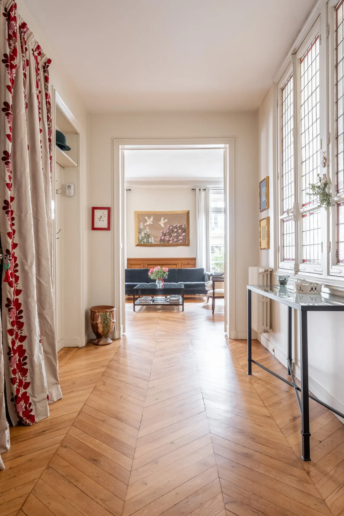 A bright living room with wood flooring and seating visible through the doorway.