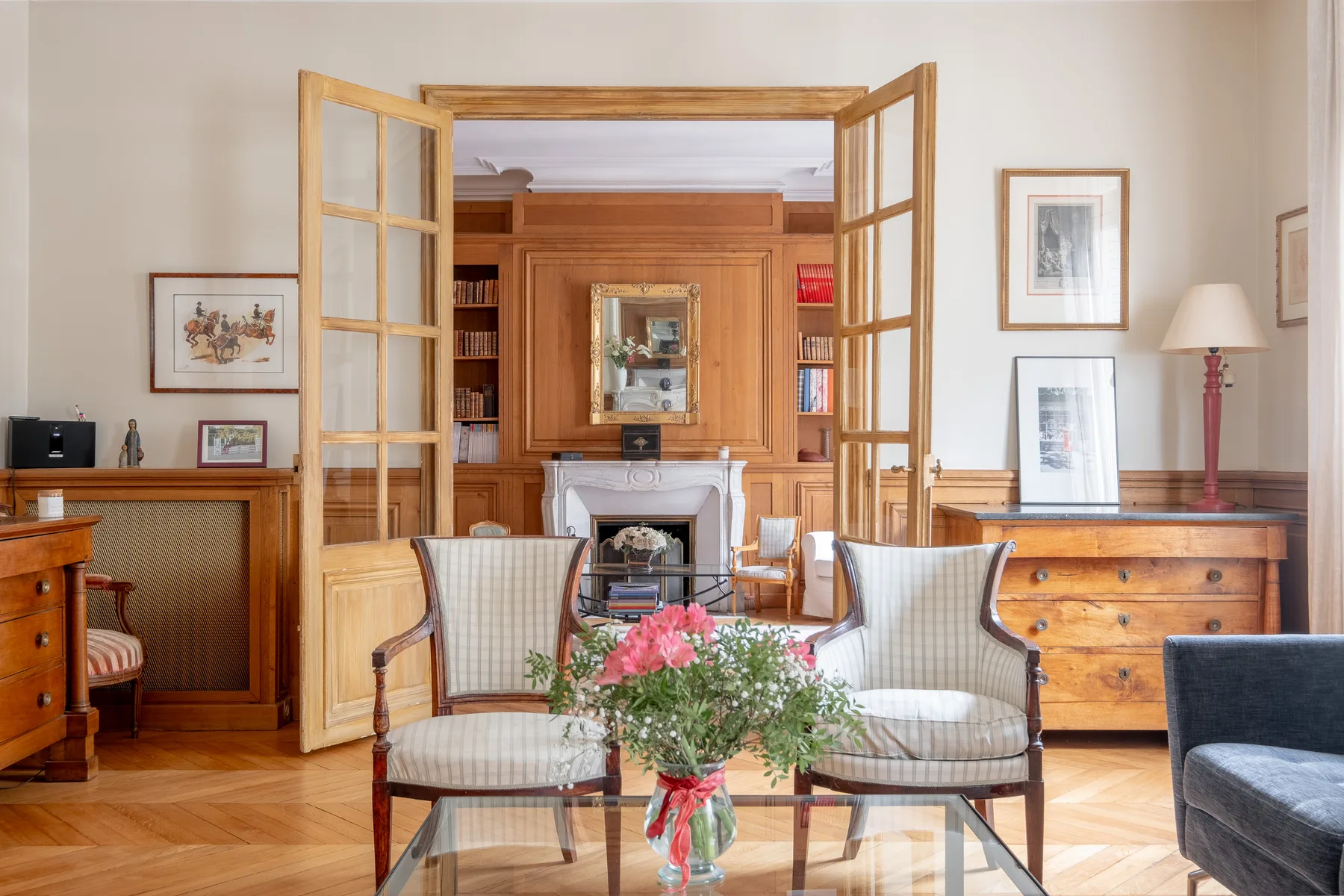 A furnished living room with seating, a fireplace, and flowers on a glass table.