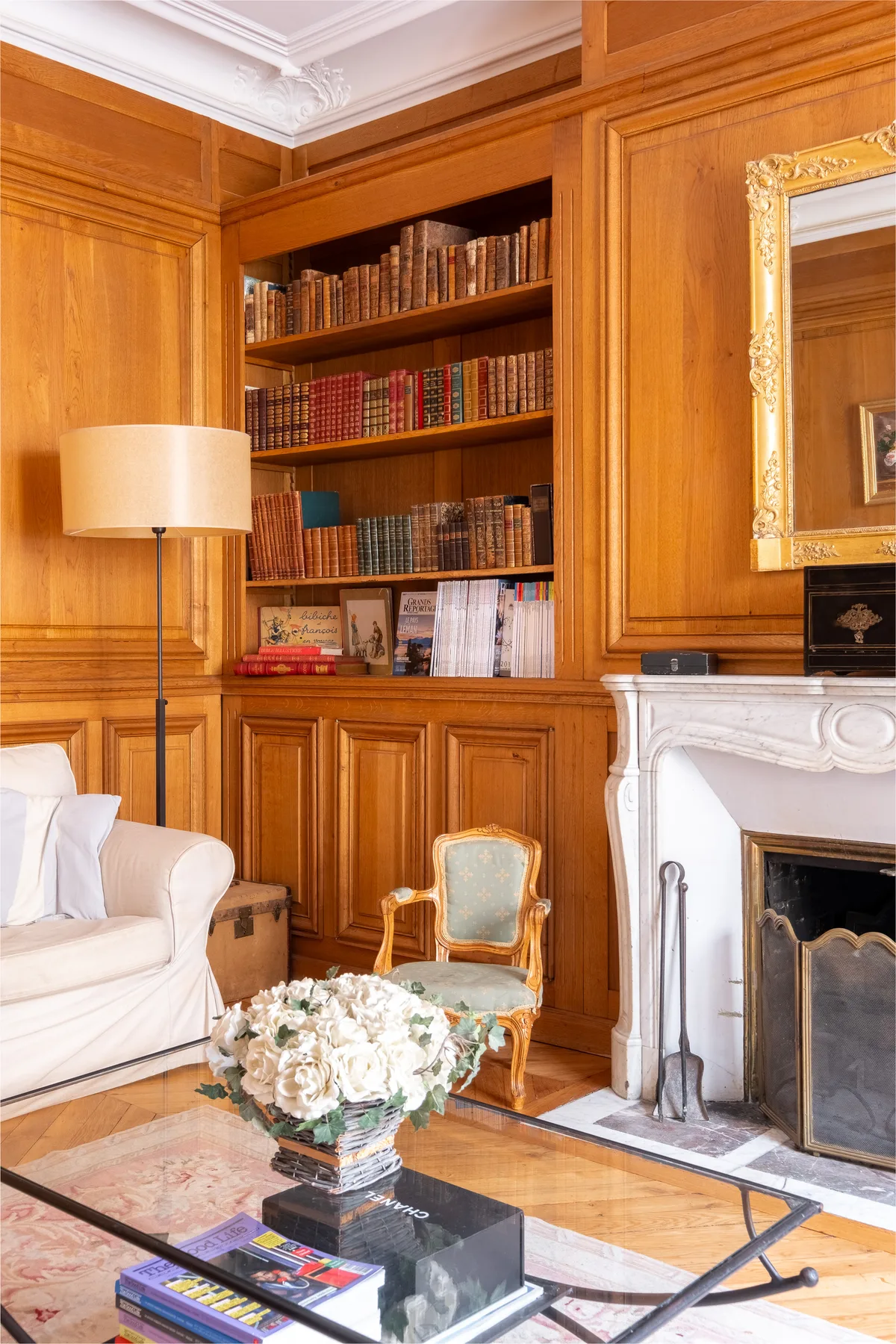 A wood-paneled living room with a bookcase, seating, and a fireplace.