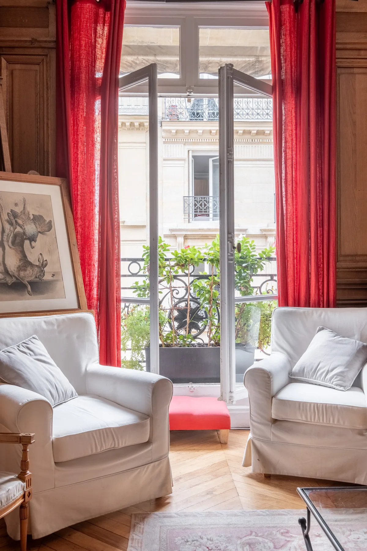 A sitting room with two armchairs facing an open balcony door.